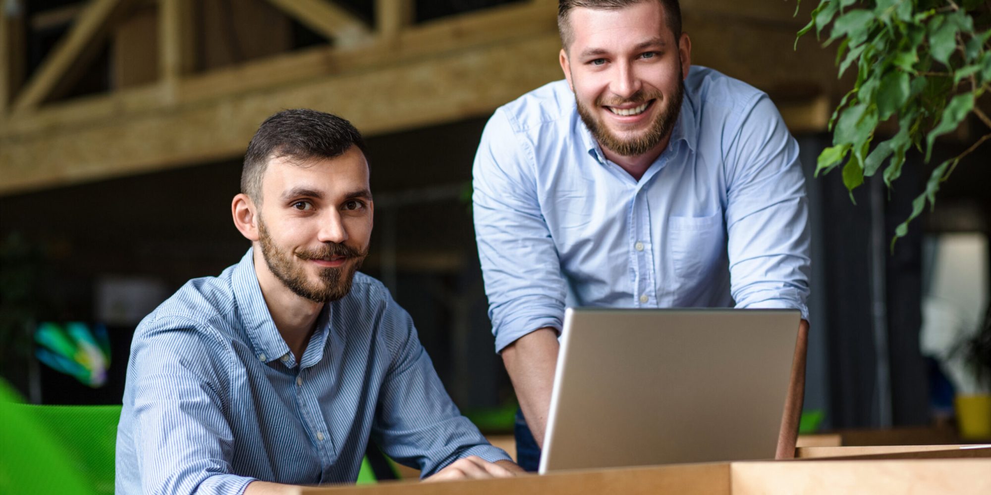 Picture of handsome businessman listening to his colleague or partner concerning ner business system while working on laptop computer in office interior.